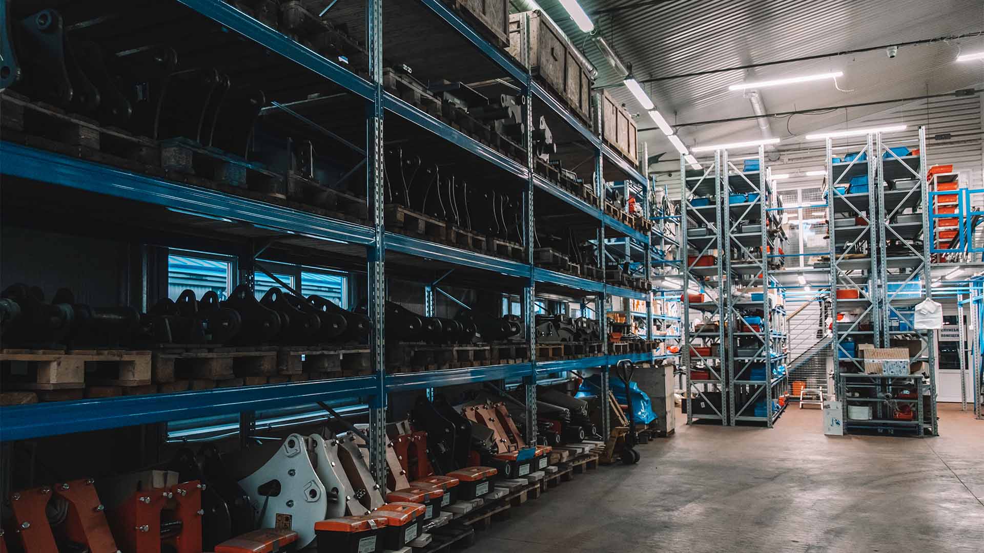 Фотография складского помещения, где находятся стеллажи с запасными частями для гидромолотов